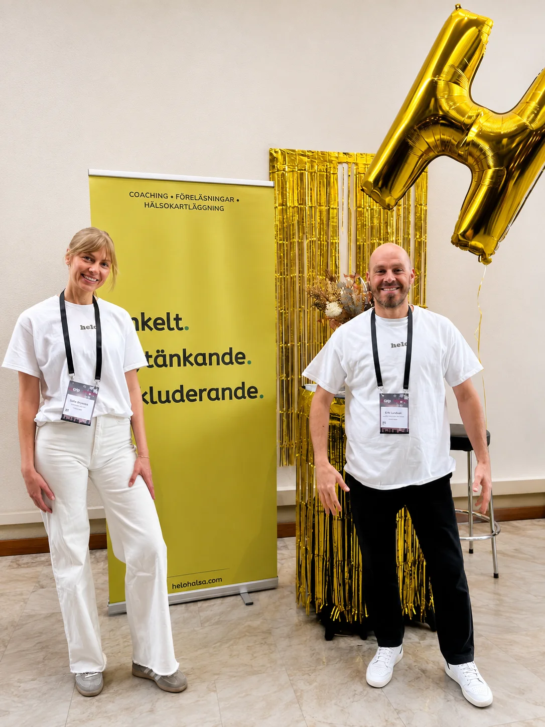 Två medarbetare från Helo Hälsa framför företagets monter på ett event